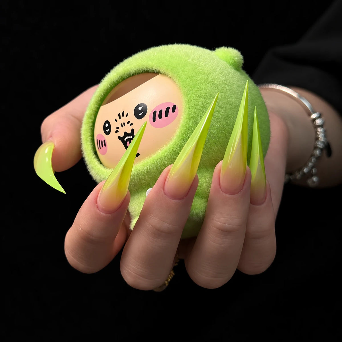 Close-up of extra long curved Dragon Claw nails featuring pointed lime green tips fading into natural nude pink bases.