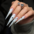 Extra-long matte white claw press-on nails with sparkling rhinestone accents, displayed on a hand against a dark background.